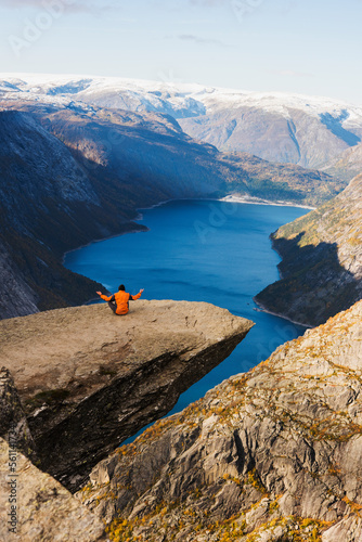 lonely hiker meditating on a huge rock of Trolltunga in Norway photo