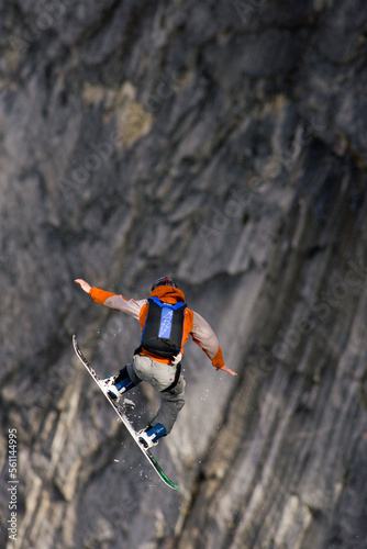 A male snowboard BASE jumper jumps off an 800 foot granite cliff. photo