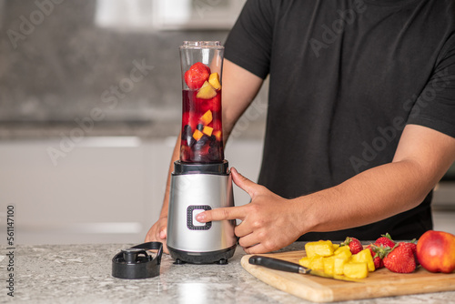 hispanic teenager preparing a smoothie on a blender