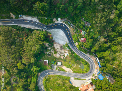 Aerial view top down drone shot above the winding mountain road between the trees rainforest,Phuket Thailand,in summer season weather, Car driving through the curve road
