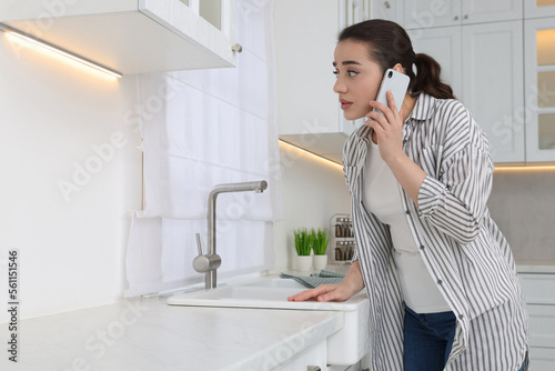Woman talking on phone and looking at wall in kitchen