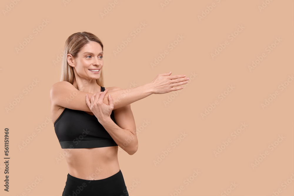 Fototapeta premium Athletic woman stretching on beige background, space for text
