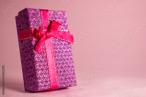 Pink gift box with bow on pink background 