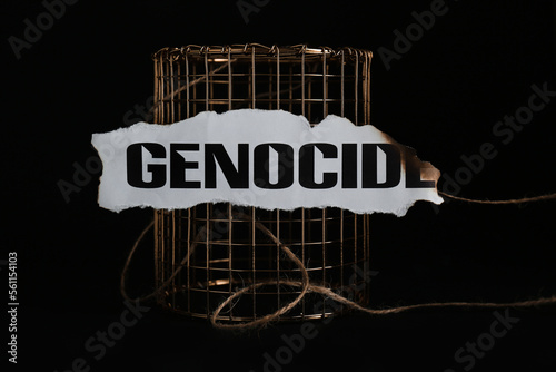 Paper with word Genocide and golden cage on black background photo