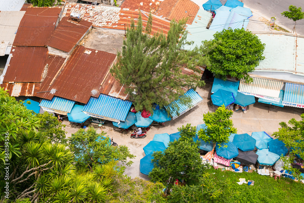 Aerial view over a congested village with rusty tin roofs and blue umbrellas at Da Nang in Vietnam