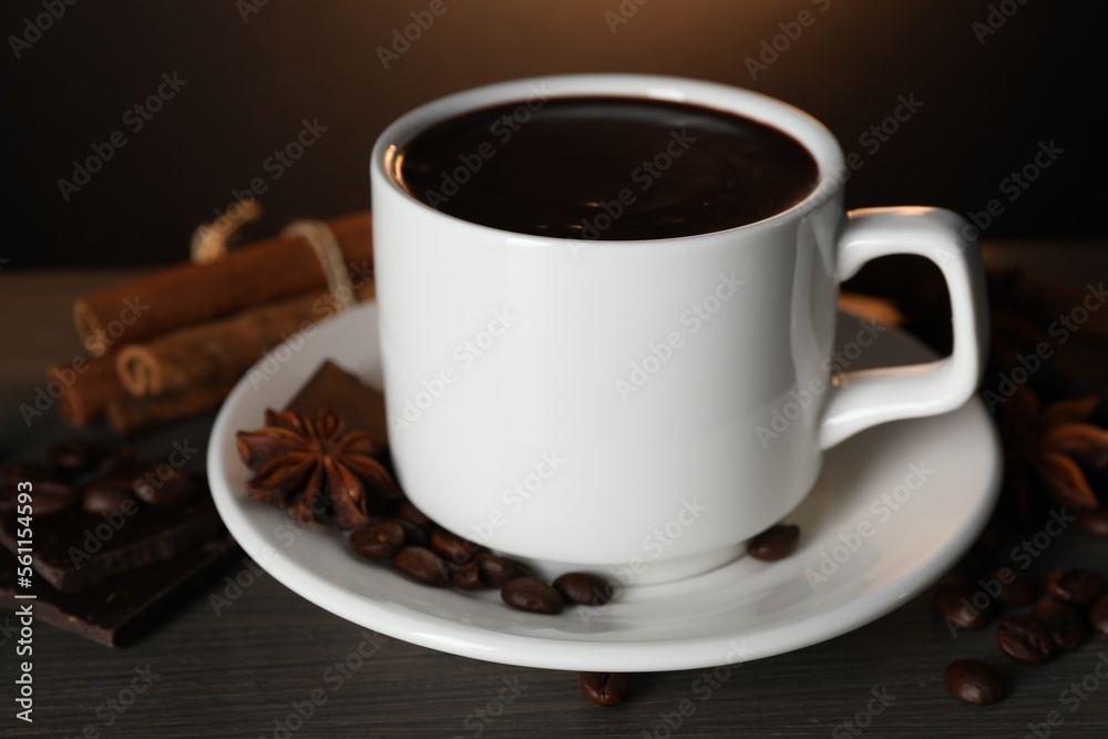 Cup of delicious hot chocolate, spices and coffee beans on wooden table Cup of delicious hot chocolate, spices and coffee beans on wooden table
