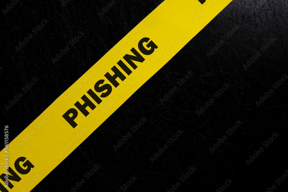 Phishing scam alert, caution and warning concept. Yellow barricade tape with word phishing in dark black background.