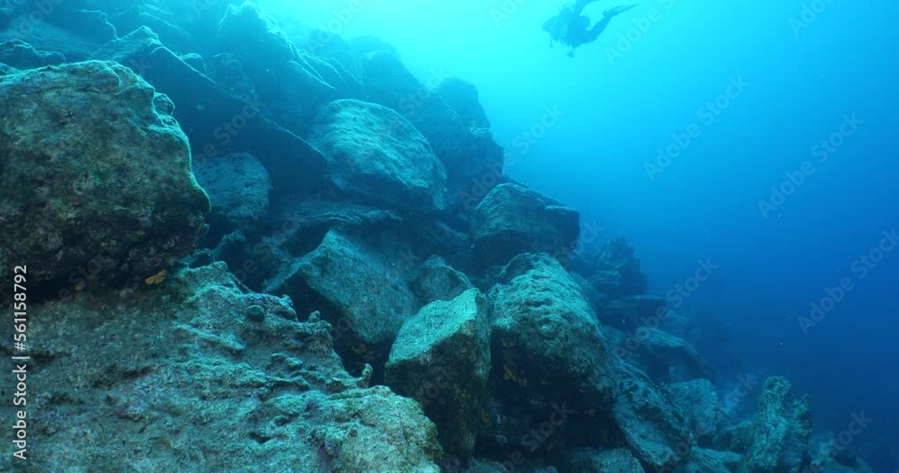 scuba diver exploring around a reef underwater deep blue water big rocks and bubbles ocean scenery scuba diver exploring around a reef underwater deep blue water big rocks and bubbles ocean scenery
