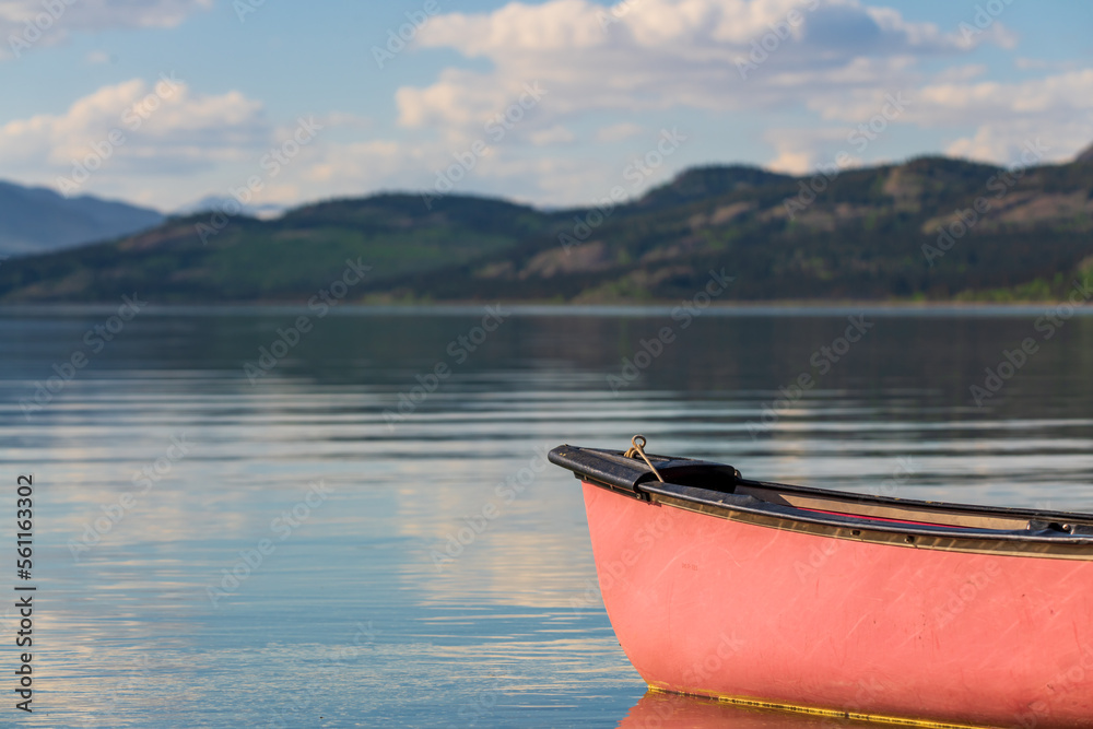 Summertime views in northern Canada with calm lake and mountain views. Red canoe in focus view. Summertime views in northern Canada with calm lake and mountain views. Red canoe in focus view.
