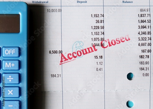 Blue calculator and pen on bank pass book with stamp ACCOUNT CLOSED, concept of bank account was terminated or disactivated , withdraw to zero balance left , unable to do any transaction