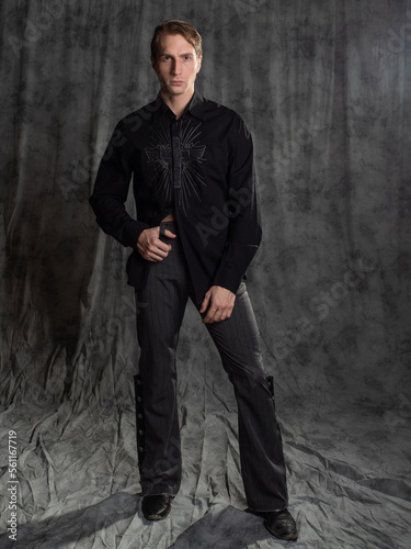 an attractive man in an elegant suit, shirt with embroidery. Photo in the studio on a gray background