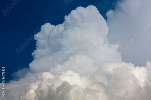 Big White fluffy cumulonimbus storm clouds in deep blue sky
