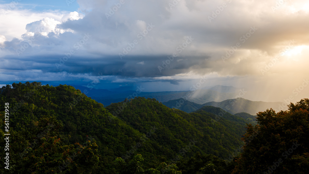 beautiful rainforest mountains landscape with big white rainy clouds at sunset
