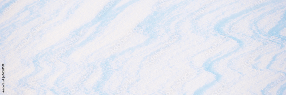 Fototapeta premium Wide panoramic winter background with snowy ground. Natural snow texture. Wind sculpted patterns on snow surface.