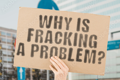 The phrase " Why is fracking a problem? " on a banner in men's hand with blurred background. Risky. Hazard. Anger. Alert. Frack. Safety. Risk. Global. Future. Energy. Disaster. Death. Climate