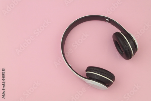Top view of black and white headphones on pink background with copy space for text.
