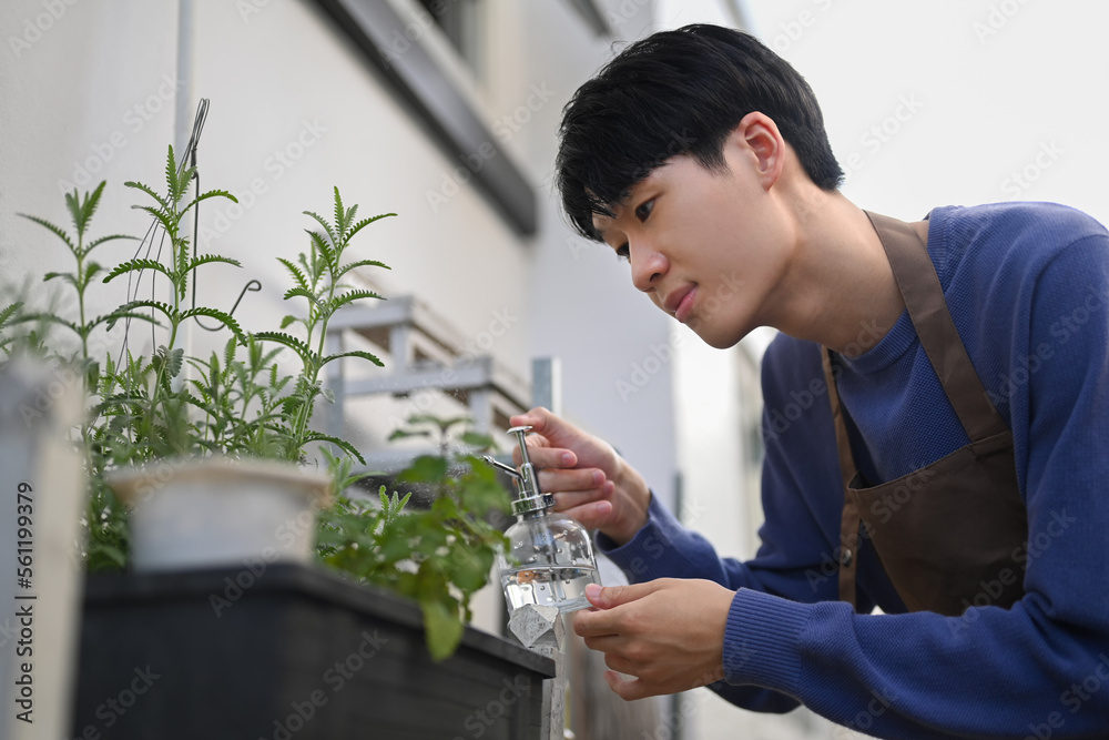 Carefree asian man in apron taking care of plants at the backyard. Gardening hobby concept Carefree asian man in apron taking care of plants at the backyard. Gardening hobby concept