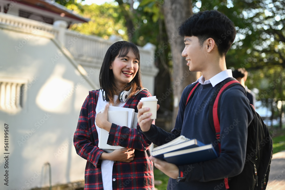 Two smiling college student walking after to college building and discussing the project or sharing the ideas Two smiling college student walking after to college building and discussing the project or sharing the ideas