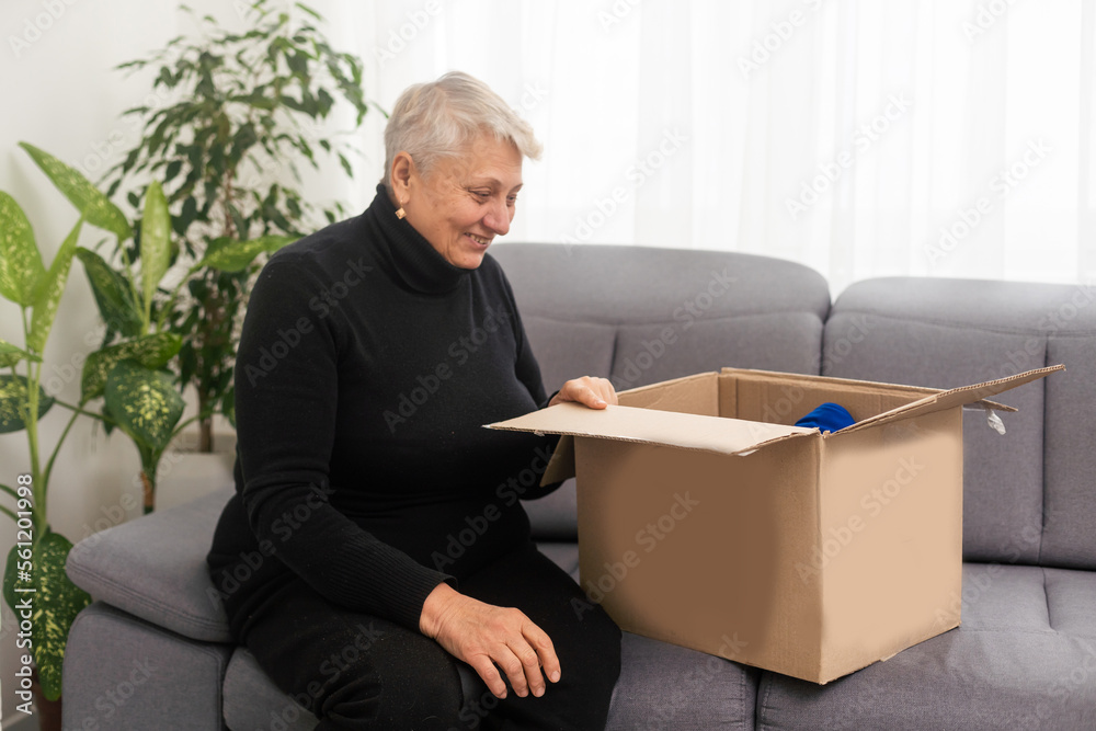 Elderly woman unpacking things in new house. Female hands opening cardboard box. Real estate, purchase, moving concept. Elderly woman unpacking things in new house. Female hands opening cardboard box. Real estate, purchase, moving concept.