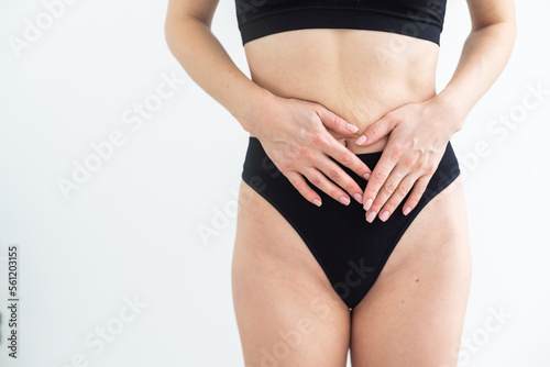 Concept of bodycare gynecology and woman's health. Cropped close up photo of woman's hand touching lower part of her abdomen, isolated on white background. © Angelov