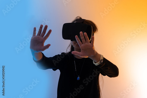 Teenage girls are having fun playing VR glasses virtual reality metaverse playing games, watching movies, listening to music, shopping. Colorful neon futuristic backgrounds, digital future technology.