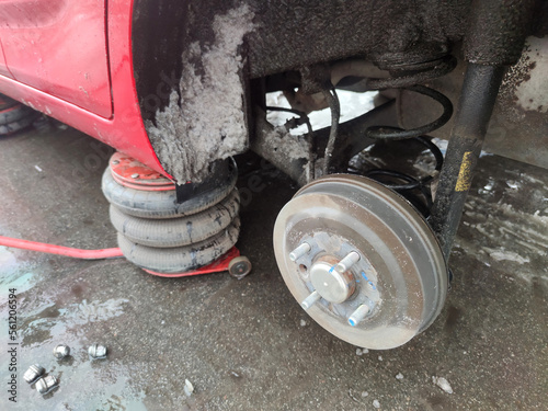 Car with rear wheel removed, lifted by hydraulic jack, car repair on the roadside