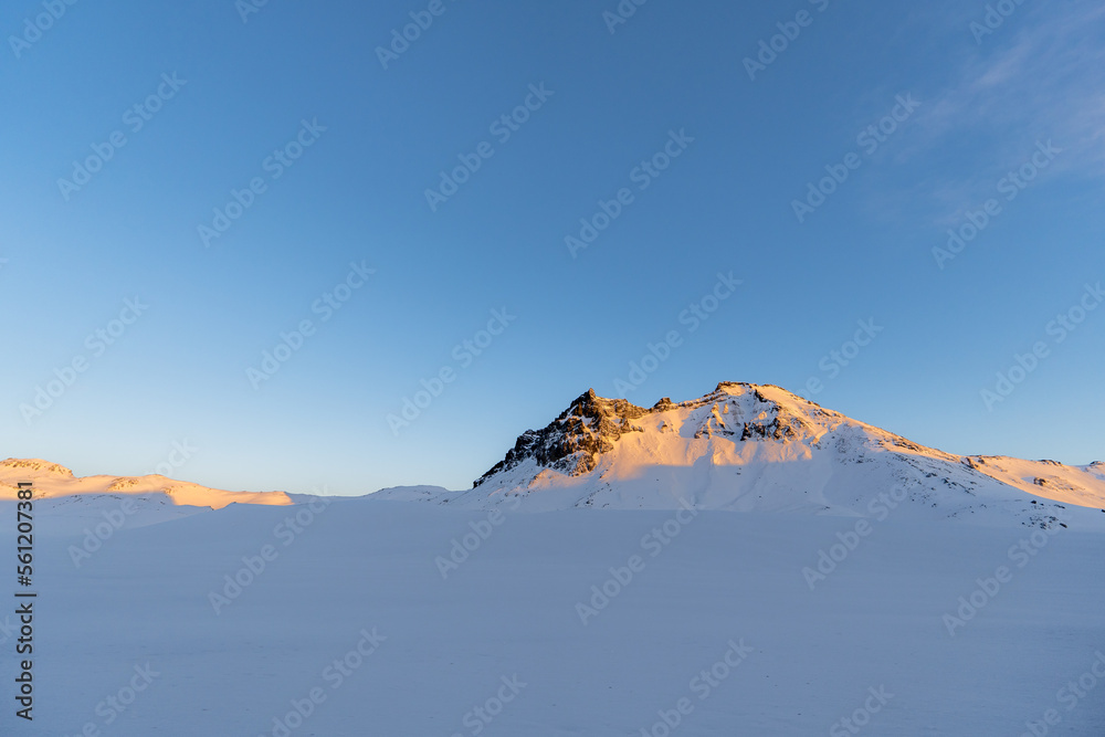 Snowy mountains lit by the sunrise sun of Iceland with all the snowy surroundings and a clear sky.