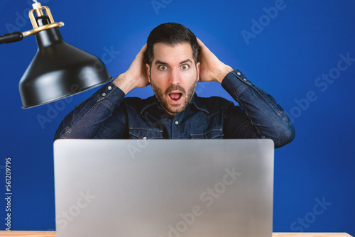 Mann schaut schockiert auf sein Laptop, Cyberattacke auf Computer, Virus, Spam