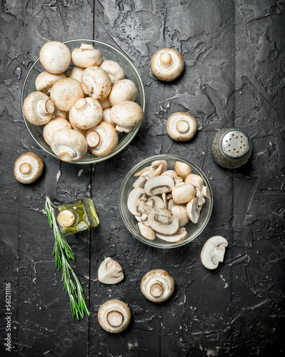 Fresh mushrooms in a bowl, bottled oil and pepper.