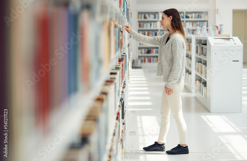 Woman, student and research in library for books, knowledge or learning at bookstore for education. Female looking at bookshelf in study for project, assignment or thesis for college scholarship photo