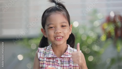 A cute Asian Thai kid girl aged 6 to 8 years old, looks healthy, holding an apple in her hand. She is eating apples. she likes to eat fruit Make her grow and be healthy. She happily eats apples. photo