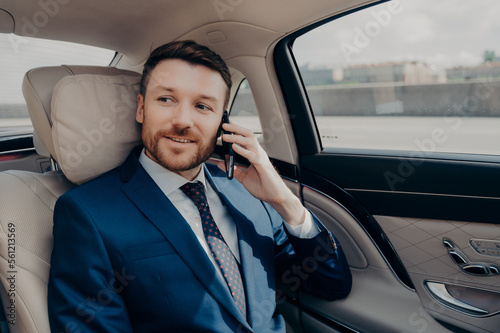 Young good looking businessman taking ride to conference while talking on phone © VK Studio