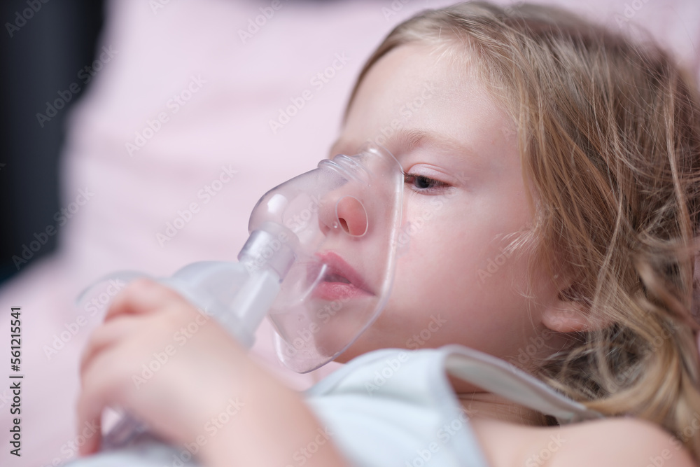 Oxygen mask of cute little girl on face on bed in hospital Oxygen mask of cute little girl on face on bed in hospital