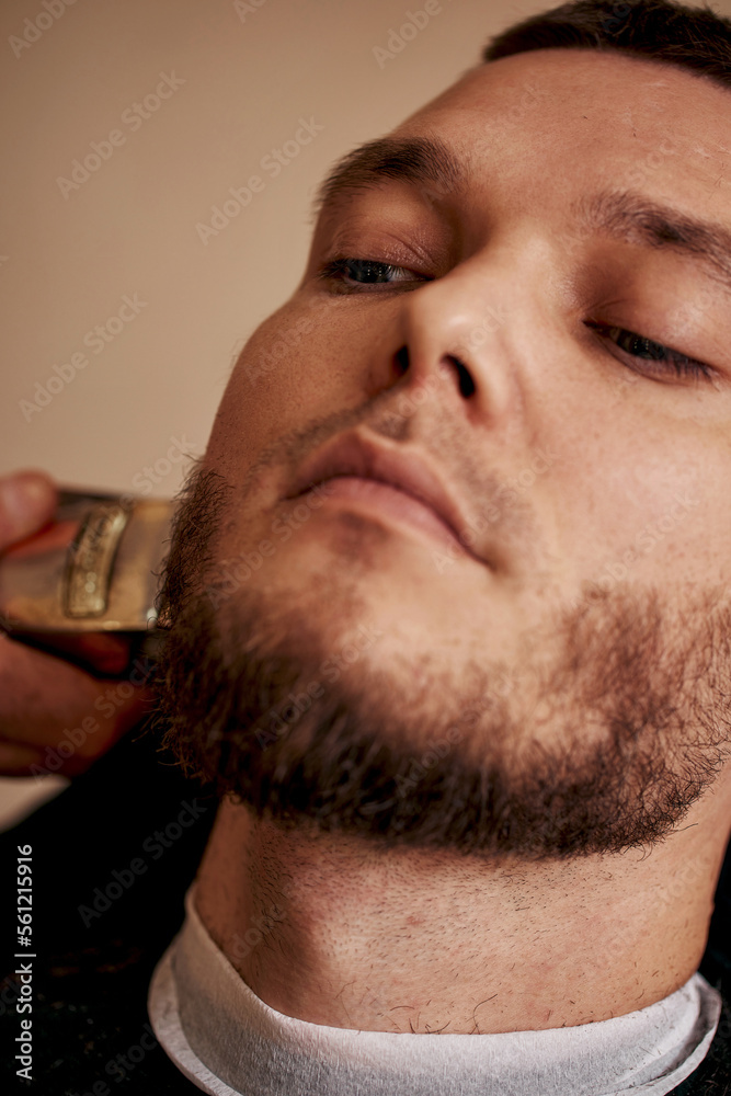 Obraz premium Barber shaving caucasian man in barber shop