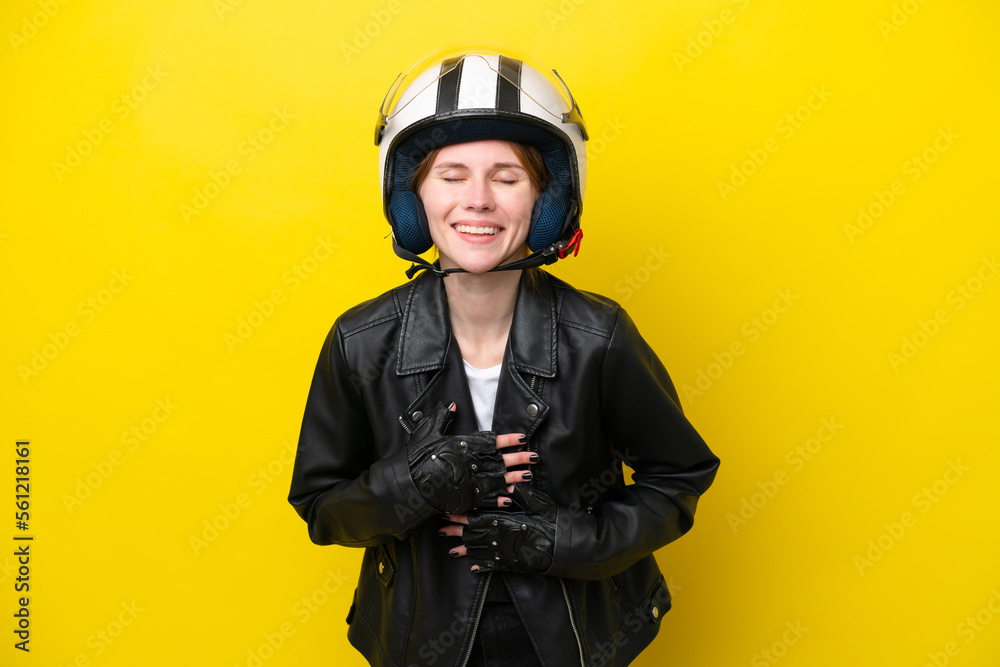 Young English woman with a motorcycle helmet isolated on yellow background smiling a lot Young English woman with a motorcycle helmet isolated on yellow background smiling a lot