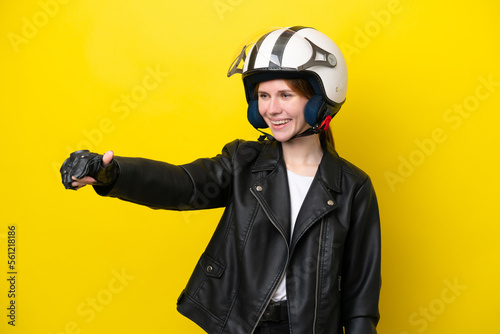 Young English woman with a motorcycle helmet isolated on yellow background giving a thumbs up gesture