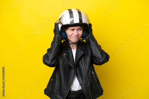 Young English woman with a motorcycle helmet isolated on yellow background frustrated and covering ears