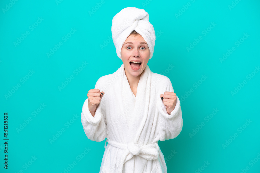 Young woman in a bathrobe isolated on blue background celebrating a victory in winner position Young woman in a bathrobe isolated on blue background celebrating a victory in winner position