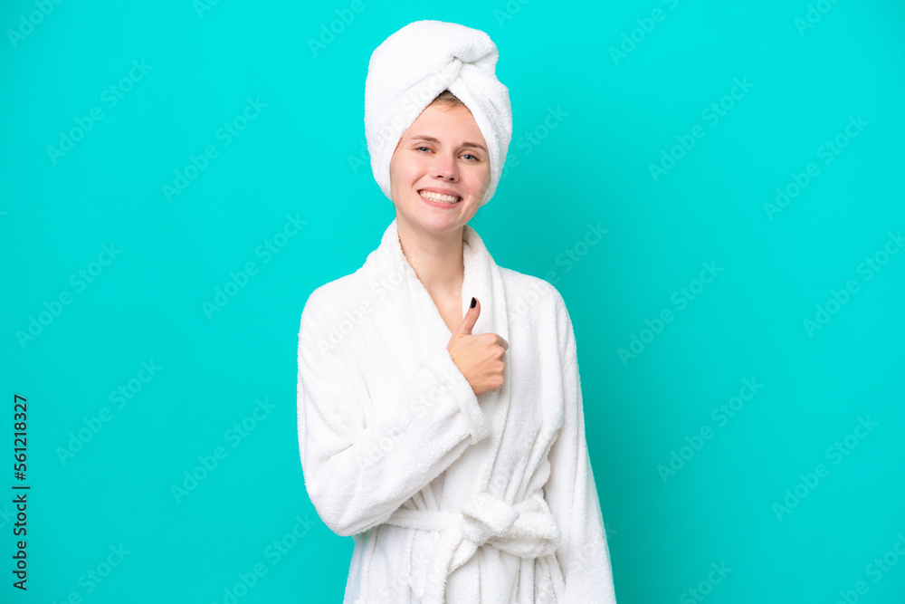 Young woman in a bathrobe isolated on blue background giving a thumbs up gesture Young woman in a bathrobe isolated on blue background giving a thumbs up gesture