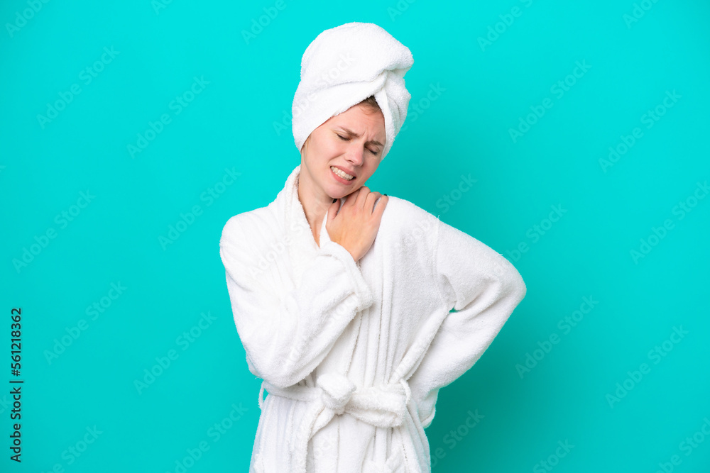 Young woman in a bathrobe isolated on blue background suffering from pain in shoulder for having made an effort Young woman in a bathrobe isolated on blue background suffering from pain in shoulder for having made an effort