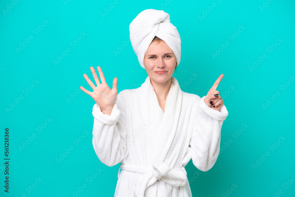 Young woman in a bathrobe isolated on blue background counting six with fingers Young woman in a bathrobe isolated on blue background counting six with fingers