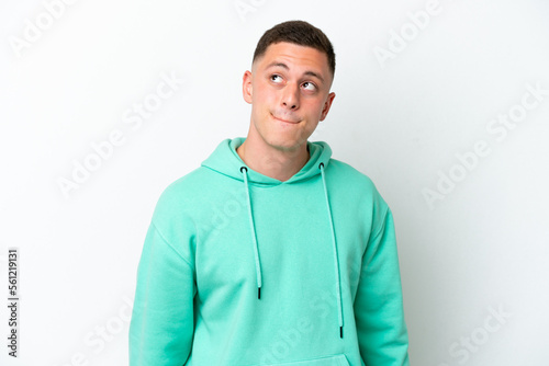 Young brazilian man isolated on white background having doubts while looking up © luismolinero