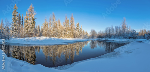 Winter landscape with reflection of the forest in the creek