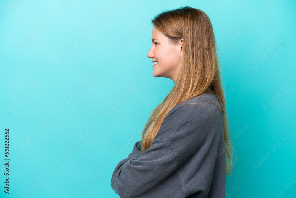 Fototapeta premium Young caucasian woman isolated on blue background in lateral position