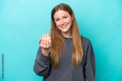 Young caucasian woman isolated on blue background inviting to come with hand. Happy that you came