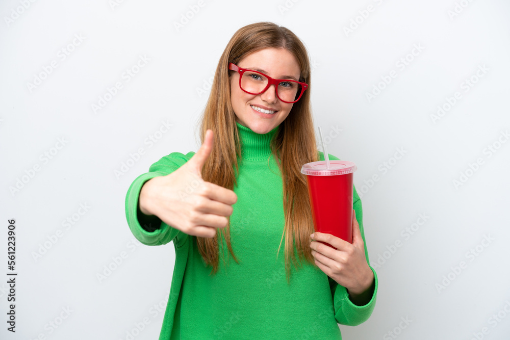 Young caucasian woman drinking soda isolated on white background with thumbs up because something good has happened Young caucasian woman drinking soda isolated on white background with thumbs up because something good has happened
