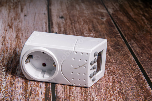 Timer with digital display in white on wooden floor a power guzzler or save electricity