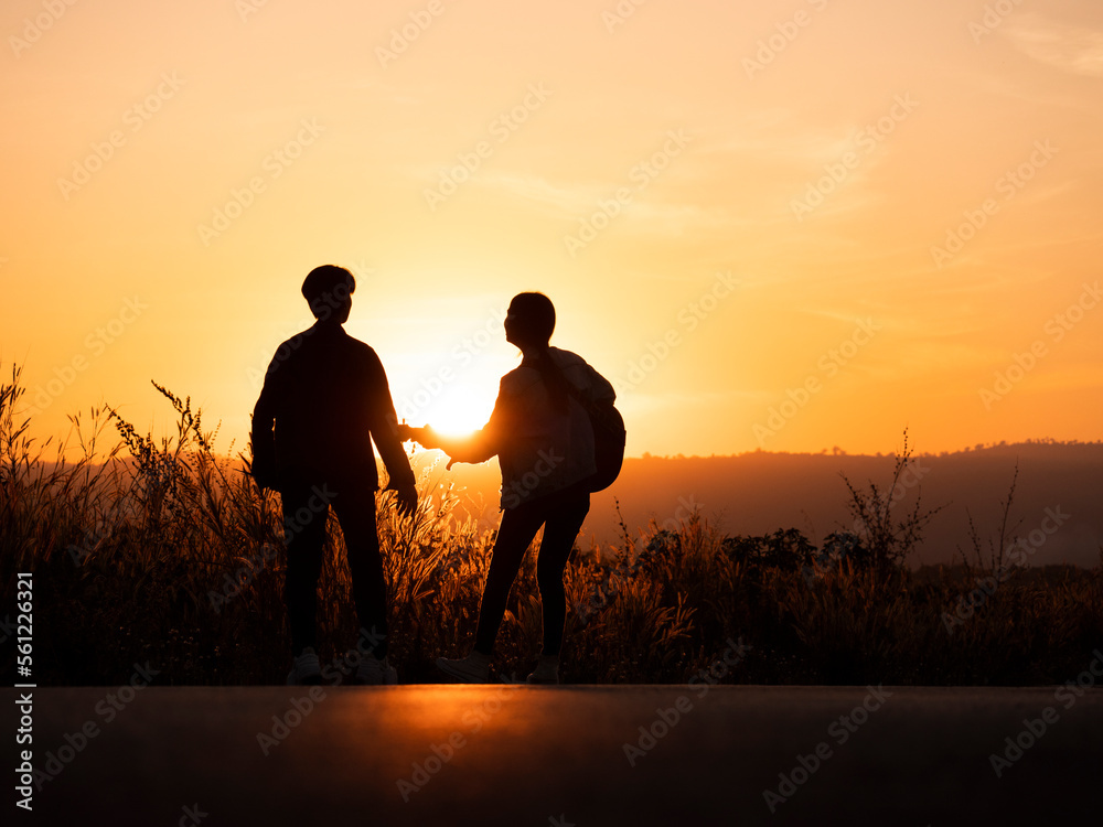 silhouette of tourist couple playing guitar against landscape during beautiful sunset, tourists enjoying sunset