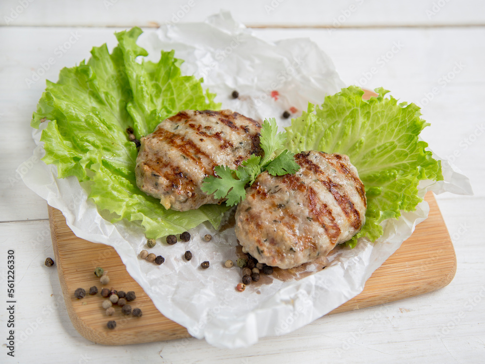 Delicious turkey poultry cutlets. dietary product. Two cutlets lie on a wooden board with a lettuce leaf.