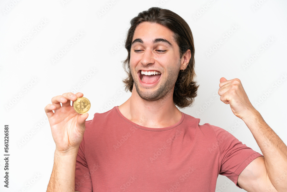 Young handsome man holding a Bitcoin isolated on white background celebrating a victory Young handsome man holding a Bitcoin isolated on white background celebrating a victory